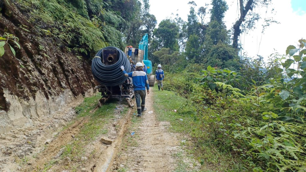 Crew hauling drill pipe along a forest trail