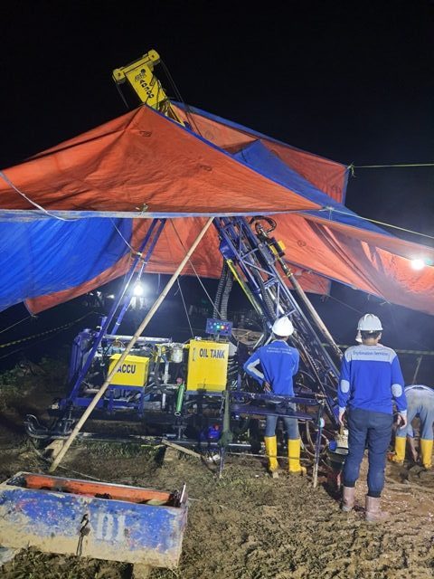 Drill rig operating at night under a tarp canopy
